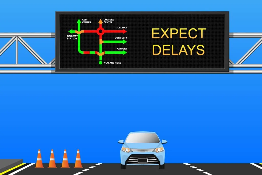 Variable message sign reading "EXPECT DELAYS" above a road with a car